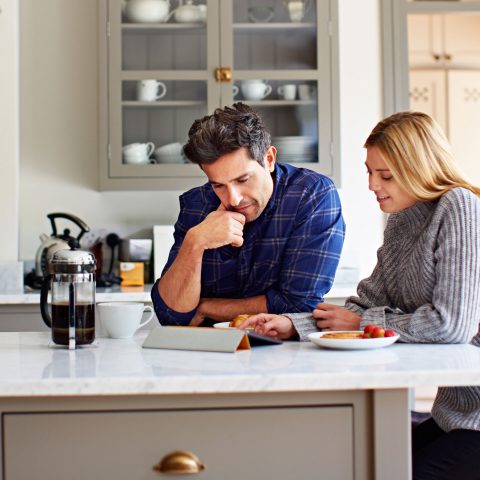 Two people in a kitchen reading documents